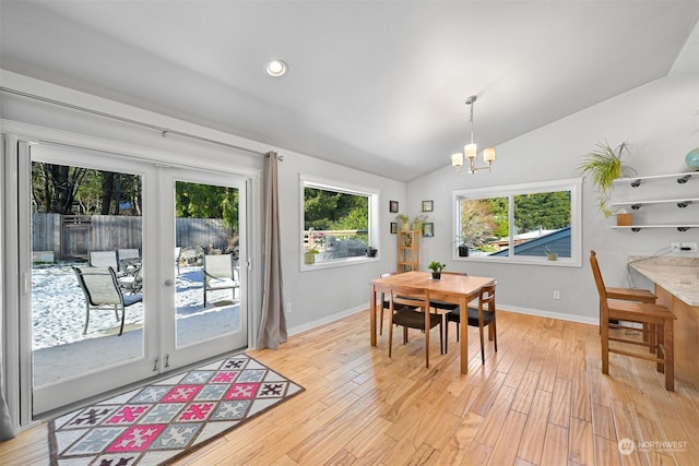 dining space with lofted ceiling, a notable chandelier, and light wood-type flooring