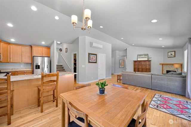 dining area with lofted ceiling, a wall mounted air conditioner, light hardwood / wood-style flooring, and a notable chandelier