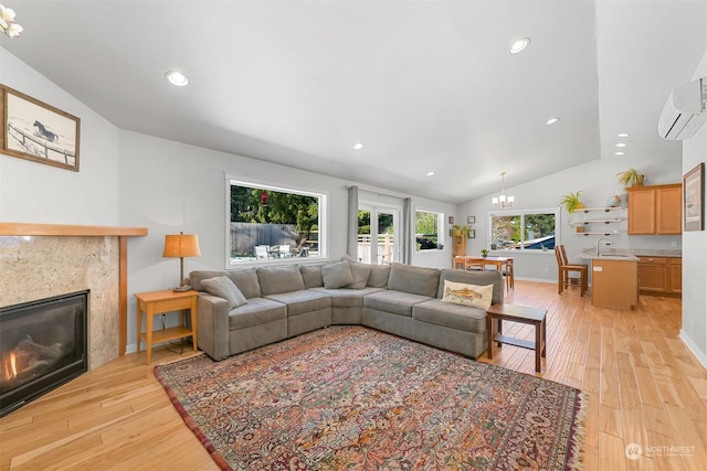 living room with lofted ceiling, a premium fireplace, a chandelier, and light hardwood / wood-style floors