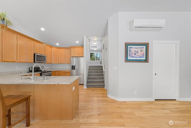 kitchen with appliances with stainless steel finishes, an AC wall unit, sink, kitchen peninsula, and light stone countertops