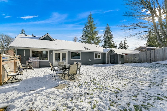 snow covered rear of property featuring french doors and a storage unit