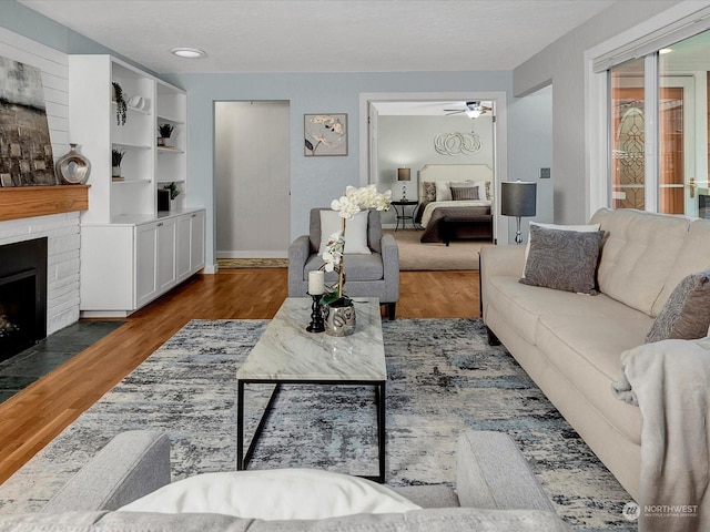 living room with a textured ceiling, wood-type flooring, and ceiling fan