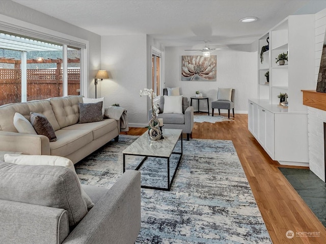 living room with hardwood / wood-style floors, a fireplace, a textured ceiling, and ceiling fan