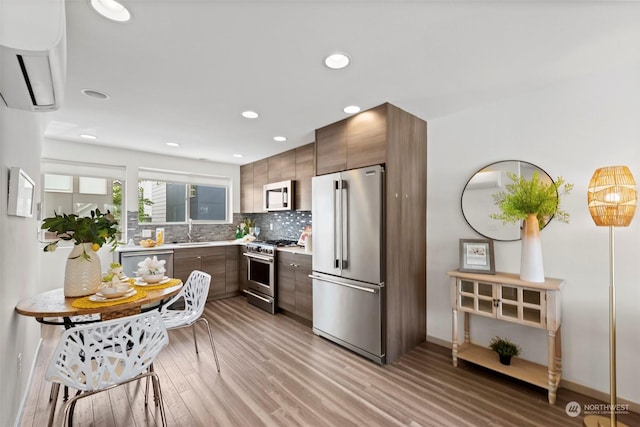 kitchen with sink, dark brown cabinets, light wood-type flooring, premium appliances, and decorative backsplash