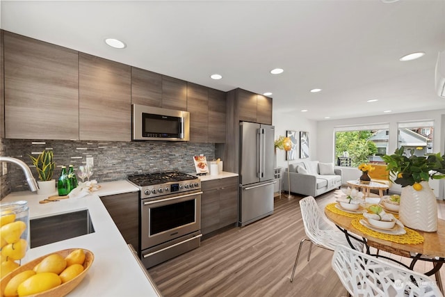 kitchen featuring dark brown cabinetry, sink, tasteful backsplash, and high quality appliances