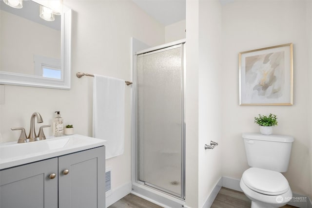 bathroom with a shower with door, vanity, wood-type flooring, and toilet