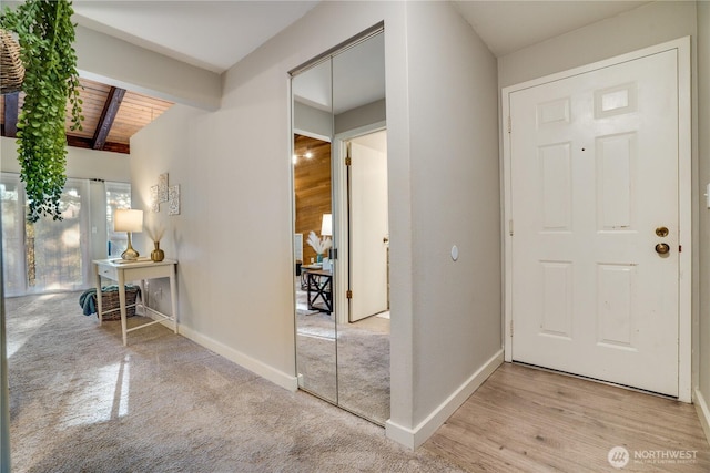 foyer with beamed ceiling, light hardwood / wood-style floors, and wooden ceiling