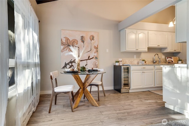 kitchen featuring sink, beverage cooler, light wood-type flooring, and white cabinets