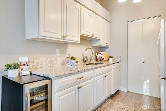 kitchen with white cabinetry, white appliances, beverage cooler, and sink