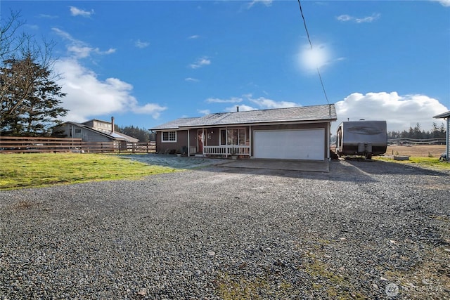 view of front of house featuring a front lawn, an attached garage, fence, and gravel driveway