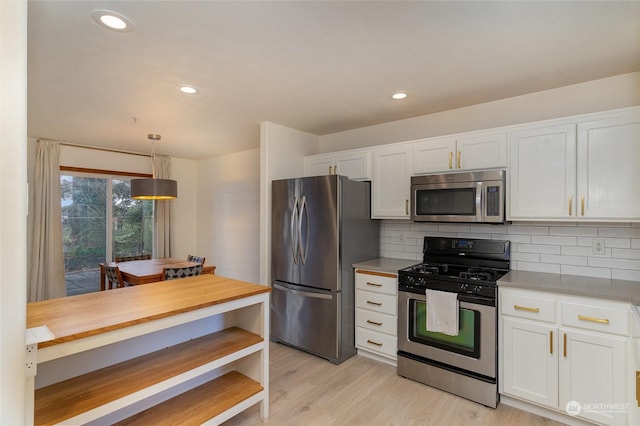 kitchen with white cabinetry, hanging light fixtures, light hardwood / wood-style floors, and appliances with stainless steel finishes