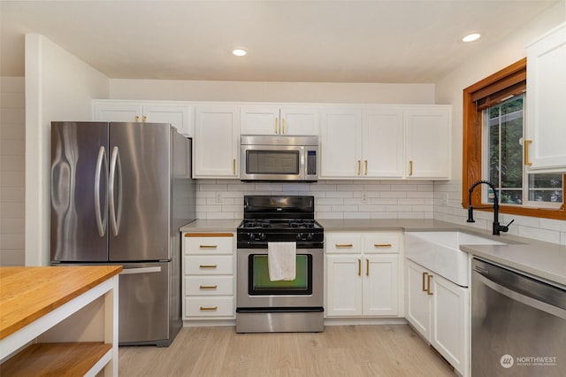 kitchen with white cabinetry, stainless steel appliances, sink, and light wood-type flooring