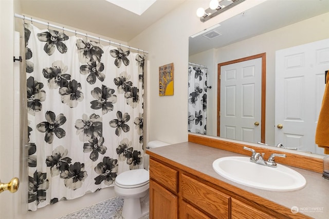 bathroom featuring vanity, toilet, a skylight, and a shower with shower curtain