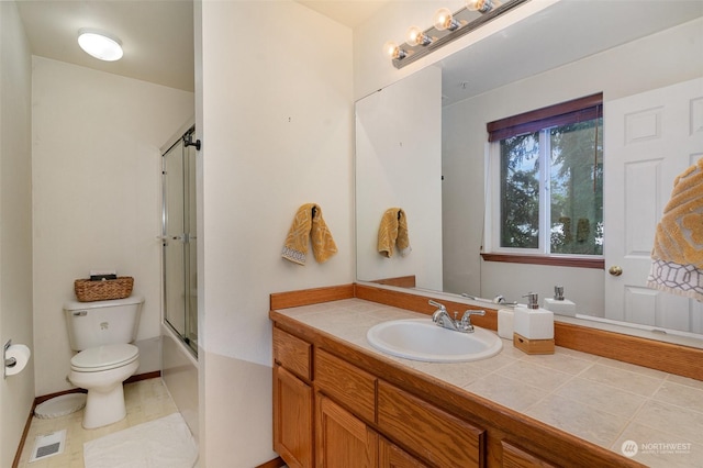 full bathroom with bath / shower combo with glass door, vanity, and toilet