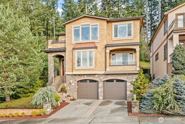 view of front of house featuring driveway, stone siding, a garage, and stucco siding