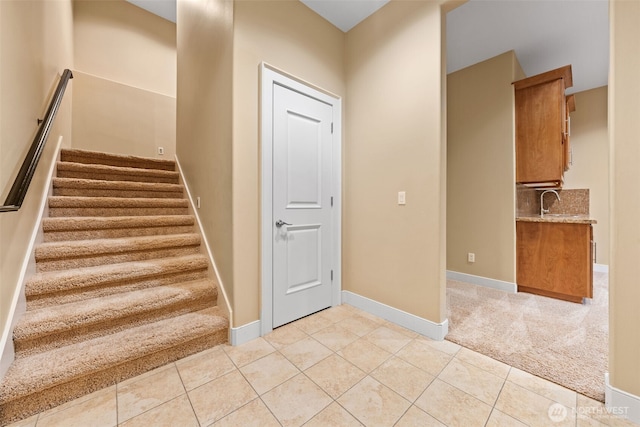 stairway featuring baseboards, carpet floors, and tile patterned floors