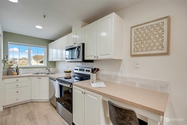 kitchen with stainless steel appliances, white cabinetry, and sink