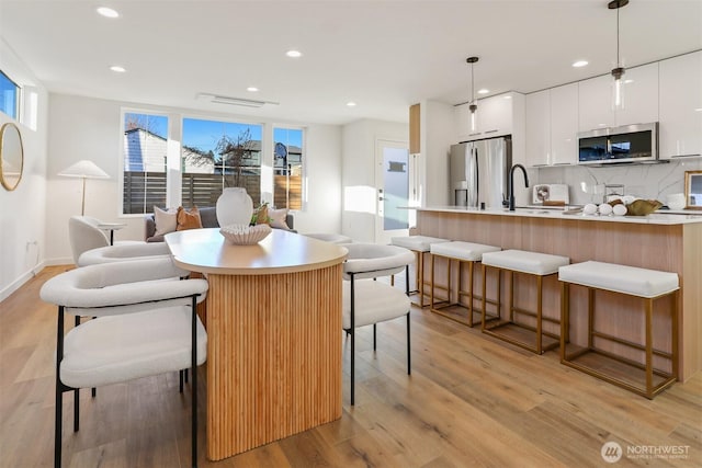 dining space with sink and light wood-type flooring