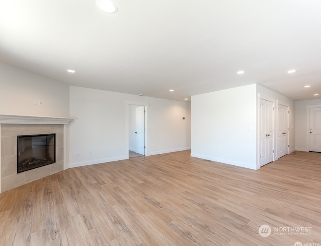 unfurnished living room featuring a tiled fireplace and light wood-type flooring