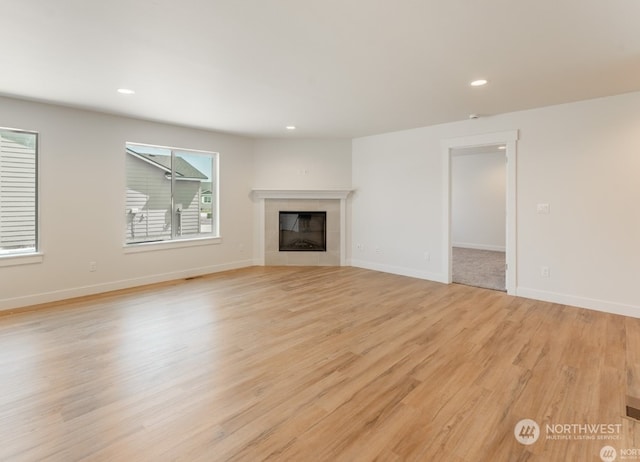 unfurnished living room featuring a tile fireplace and light wood-type flooring