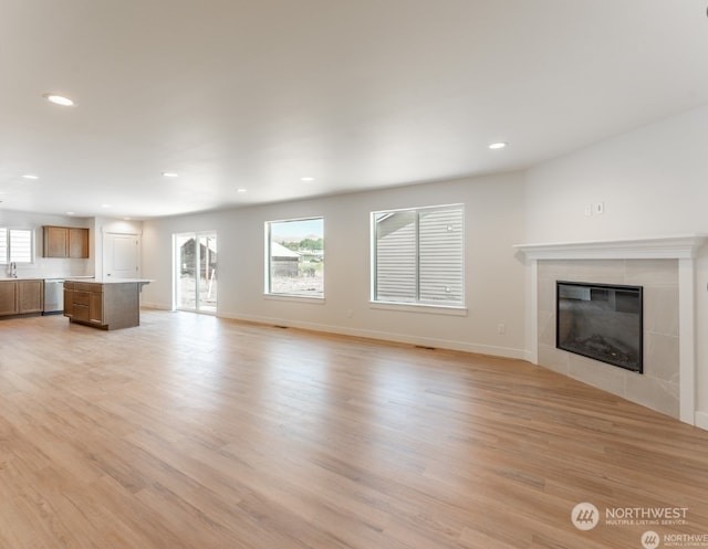 unfurnished living room with sink, a fireplace, and light hardwood / wood-style floors