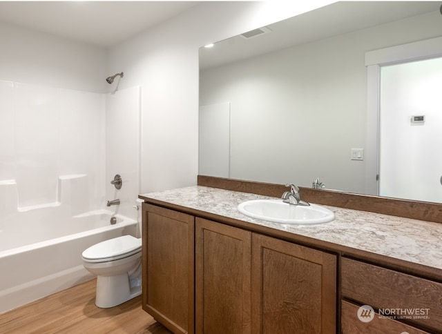 full bathroom with wood-type flooring, vanity, shower / bathtub combination, and toilet