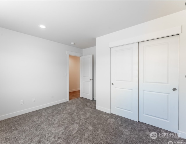 unfurnished bedroom with dark carpet and a closet