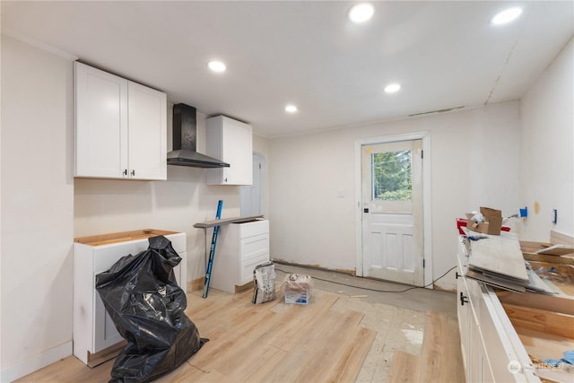 kitchen with wall chimney range hood, light hardwood / wood-style flooring, and white cabinets