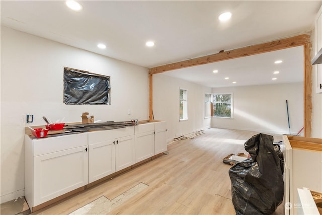 bar featuring white cabinetry, beam ceiling, and light hardwood / wood-style flooring