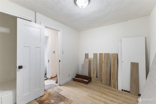 unfurnished room featuring light hardwood / wood-style flooring and a textured ceiling