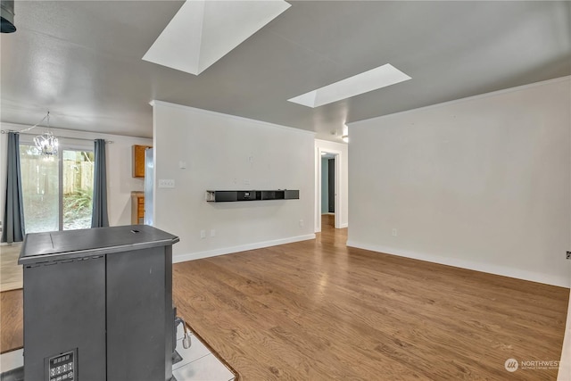 unfurnished living room with hardwood / wood-style floors, a notable chandelier, and a skylight