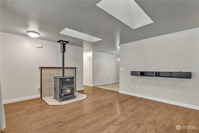 unfurnished living room with crown molding, a skylight, hardwood / wood-style floors, and a wood stove