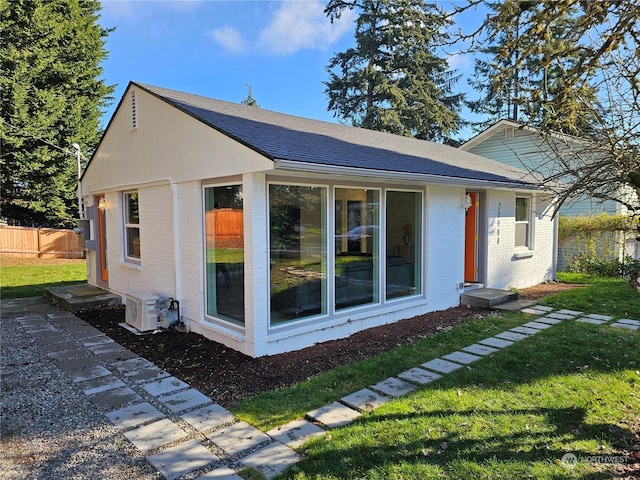 view of side of home with ac unit and a lawn