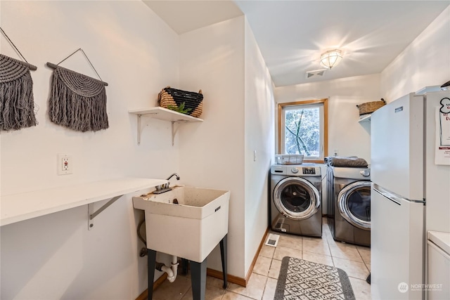 clothes washing area with sink, light tile patterned floors, and independent washer and dryer