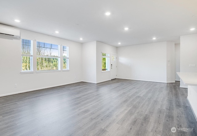 unfurnished room with a wall mounted AC and hardwood / wood-style floors