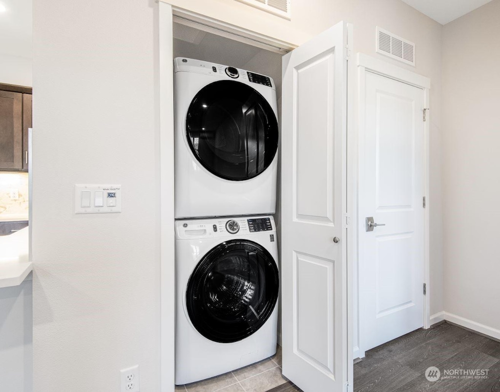 clothes washing area with stacked washer / drying machine and wood-type flooring