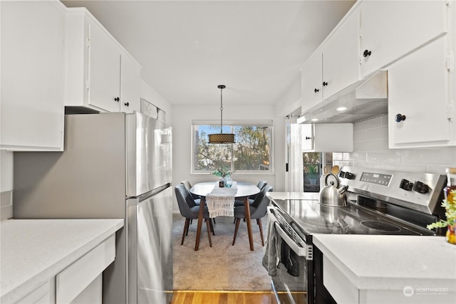 kitchen featuring appliances with stainless steel finishes, tasteful backsplash, white cabinets, hanging light fixtures, and light hardwood / wood-style floors