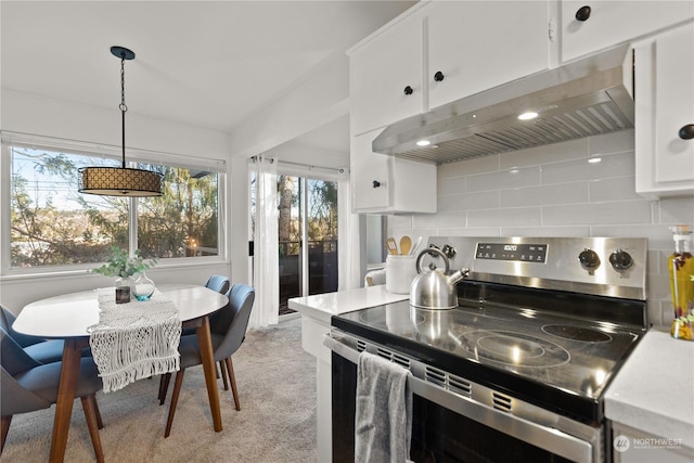 kitchen featuring white cabinetry, tasteful backsplash, hanging light fixtures, light carpet, and electric stove