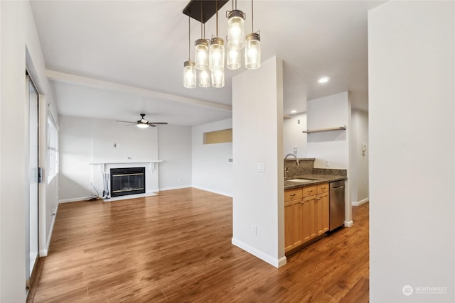 unfurnished living room with hardwood / wood-style flooring, sink, and ceiling fan