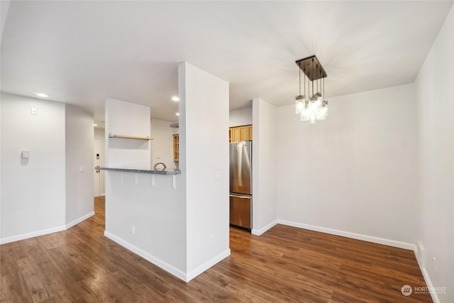 interior space featuring pendant lighting, dark hardwood / wood-style flooring, a notable chandelier, and stainless steel fridge