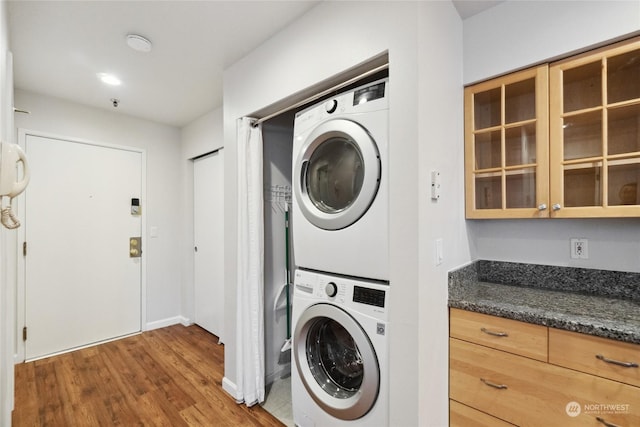 clothes washing area with dark hardwood / wood-style floors and stacked washing maching and dryer