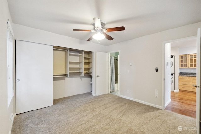 unfurnished bedroom with carpet floors, a closet, ceiling fan, and stacked washing maching and dryer