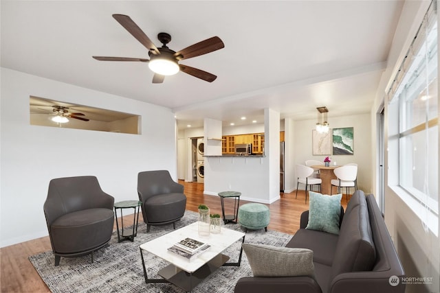 living room featuring ceiling fan, stacked washer and dryer, and hardwood / wood-style floors