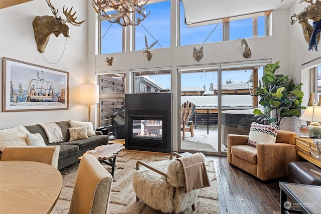 living room with a multi sided fireplace, dark hardwood / wood-style floors, and a chandelier