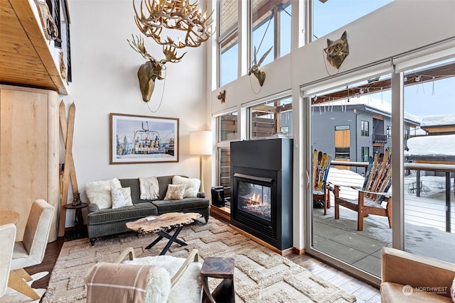 living room featuring a high ceiling, a notable chandelier, and light hardwood / wood-style floors