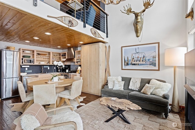 living room featuring wood ceiling, a towering ceiling, dark hardwood / wood-style floors, and sink