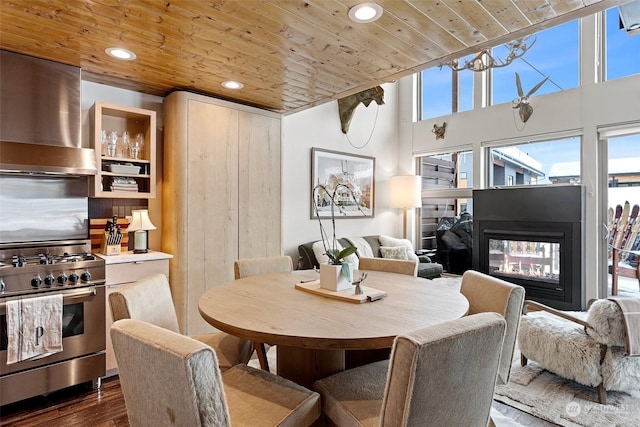 dining room with dark hardwood / wood-style flooring, wooden ceiling, and a multi sided fireplace