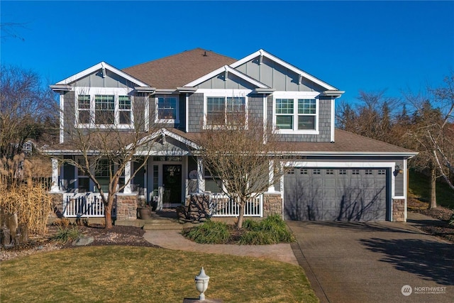 craftsman-style home with a garage, a front lawn, and covered porch