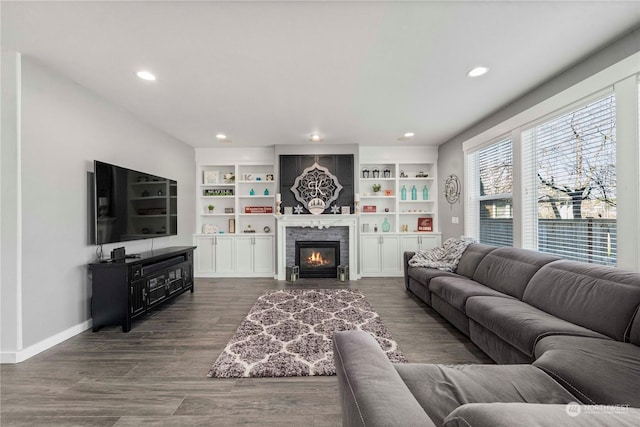 living room featuring built in features, a fireplace, and dark hardwood / wood-style flooring