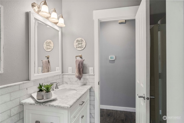 bathroom with hardwood / wood-style flooring, vanity, and tile walls